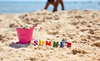 opschrift zomer Aan de zand tegen de blauw zee foto