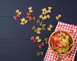 rauw pasta in de het formulier van bogen in een houten ronde bord Aan een blauw houten achtergrond foto