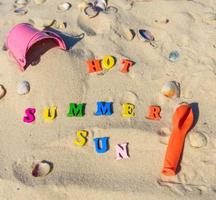 achtergrond in de zand met inscripties zomer, zon, heet foto