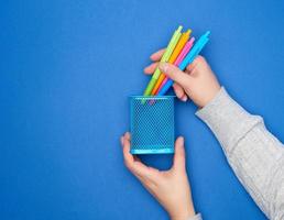 vrouw handen Holding veelkleurig plastic pennen voor tekening en een metalen blauw schrijfbehoeften staan foto