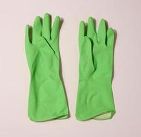 paar- van groen beschermend rubber handschoenen voor schoonmaak Aan een beige achtergrond foto