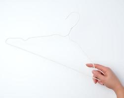 hand- houdt een wit ijzer leeg hanger Aan een wit achtergrond foto