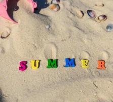 opschrift zomer gemaakt van houten brieven Aan de geel zand foto