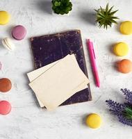 gebakken ronde macarons, leeg ansichtkaarten, notitieboekje, roze pen foto