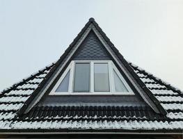 Open dak venster in velux stijl met zwart dak tegels gedekt in wit sneeuw foto