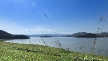 voorkant visie van groen gras. en achtergrond landschap van eiland Aan de reservoir onder blauw lucht. Bij kaeng krachan reservoir, phetchaburi, Thailand. foto