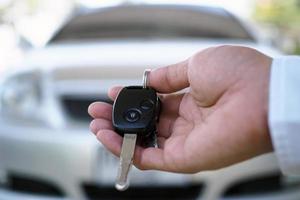 de auto eigenaar is staand de auto sleutels naar de koper. gebruikt auto verkoop foto