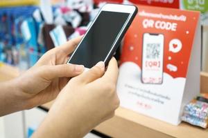 handen gebruik de telefoon naar scannen de qr code naar te ontvangen kortingen Aan aankopen in de afdeling op te slaan. foto