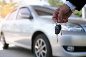 de auto eigenaar is staand de auto sleutels naar de koper. gebruikt auto verkoop foto