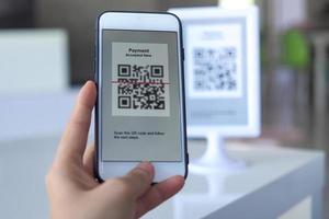 vrouw hand- Holding smartphone, scannen streepjescode voor contactloos betaling in de winkel foto