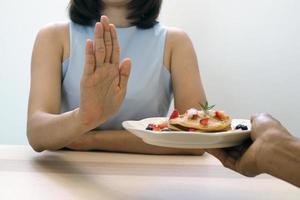 de Dames gebruikt naar Duwen de toetje bord met de mensen. Doen niet eten desserts voor gewicht verlies. foto