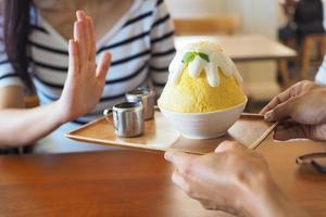 Mens handen Bezig met verzenden bingsu naar een vrouw. maar Dames Duwen hun handen. ze geweigerd aan het eten allemaal soorten van snoepgoed. vermijden suiker en desserts voor mooi zo Gezondheid concept. foto