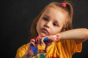 verdrietig meisje in kleurrijk holi kleuren tonen hart vormig teken met handen, liefde teken. Indisch festival van kleuren holi. foto