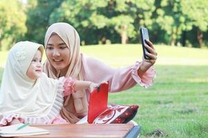 moslimmoeder en dochter nemen een gelukkige selfie in het park foto