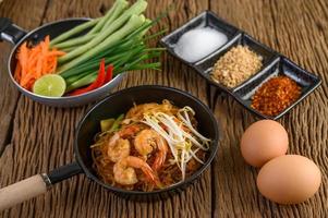 pad thai garnalen in een zwarte pan met eieren en kruiden foto
