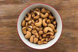 cashewnoten in witte kom op houten tafel foto