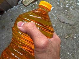 mannetje hand- Holding een fles van Koken olie foto