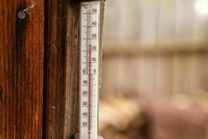 een straat thermometer blijft hangen Aan de muur van een houten huis. foto