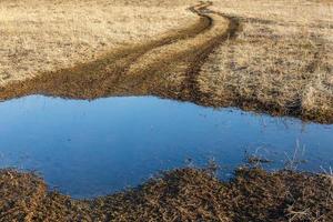 land weg in vroeg voorjaar seizoen. modder en plas foto