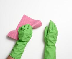 hand- in een groen rubber handschoen houdt een zacht spons voor schoonmaak oppervlakken Aan een wit achtergrond foto