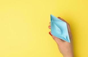 vrouw hand- houden een blauw papier boot Aan een geel achtergrond foto