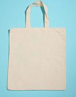 leeg linnen eco vriendelijk beige canvas tote zak voor branding Aan blauw achtergrond. Doorzichtig herbruikbaar zak voor boodschappen, bespotten omhoog foto