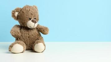 schattig bruin teddy beer zittend Aan een wit tafel, blauw achtergrond foto