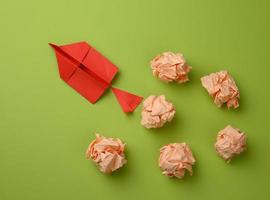 rood papier vliegtuig en verfrommeld papier ballen Aan een groen achtergrond, top visie. de concept van vinden vernieuwend ideeën foto