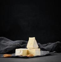 ronde Brie kaas Aan zwart verfrommeld papier, houten tafel foto