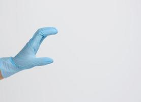 dokter hand- in een blauw medisch handschoen houdt een voorwerp Aan een wit achtergrond. kopiëren ruimte, houden ieder voorwerp foto