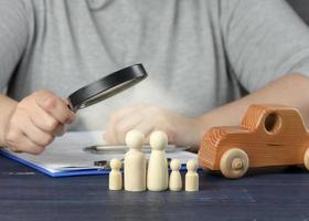 vrouw hand- onderzoekt houten figuren van de familie in een vergroten glas. de concept van aan het studeren de credit geschiedenis van de lener foto