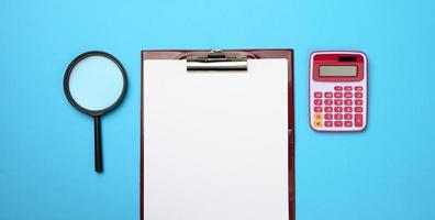 roze rekenmachine, map met blanco wit lakens en zwart vergrootglas Aan een blauw achtergrond. banier voor bedrijf foto