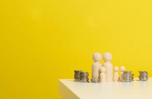 stack van metaal munten en houten figuren van mannen Aan een wit tafel. spaargeld en uitgaven, familie begroting, subsidies van de staat foto