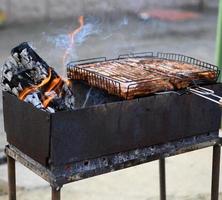 metaal koperslager met brandend hout en vlees Aan de grill, barbecue foto