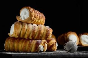 gebakken buisjes gevulde met geslagen ei blanken room Aan een zwart houten keuken bord foto