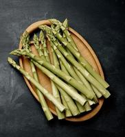 bundel van vers rauw asperges Aan een houten zwart keuken bord, een gezond Product foto