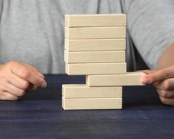hand- trekt een houten blok uit van de stapel. balans concept, situatie controle foto
