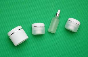 kan, fles en leeg wit plastic buizen voor schoonheidsmiddelen Aan een groen achtergrond. verpakking voor room, gel, serum, reclame en Product Promotie, bespotten omhoog foto