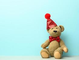 bruin teddy beer in een rood pet zit Aan een blauw achtergrond foto