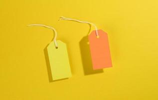 blanco rechthoekig papier geel en oranje prijs tags met wit touw Aan geel achtergrond foto