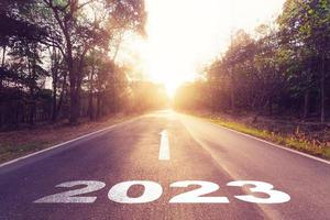 leeg asfalt weg en nieuw jaar 2023 concept. het rijden Aan een leeg weg naar doelen 2023 met zonsondergang. foto