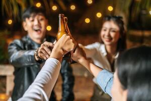 portret van gelukkig Aziatisch vrienden hebben avondeten partij samen - jong mensen zittend Bij bar tafel roosteren bier bril avondeten buitenshuis - mensen, voedsel, drinken levensstijl, nieuw jaar viering concept. foto