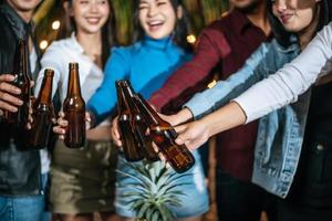 portret van gelukkig Aziatisch vrienden hebben avondeten partij samen - jong mensen roosteren bier bril avondeten buitenshuis - mensen, voedsel, drinken levensstijl, nieuw jaar viering concept. foto