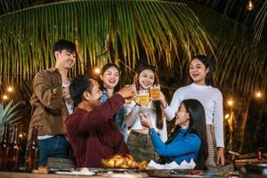 portret van gelukkig Aziatisch vrienden hebben avondeten partij samen - jong mensen roosteren bier bril avondeten buitenshuis - mensen, voedsel, drinken levensstijl, nieuw jaar viering concept. foto