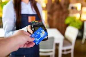 contactloos betaling concept, vrouw Holding credit kaart in de buurt nfc technologie Aan balie, cliënt maken transactie betalen Bill Aan terminal rfid Kassa machine in restaurant op te slaan, dichtbij omhoog visie foto