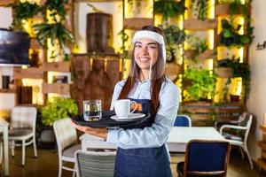 vrouw serveerster vervelend gezicht schild, vizier serveert de koffie in restaurant gedurende coronavirus pandemisch vertegenwoordigen nieuw normaal concept foto