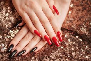 handen van een jong meisje met rood en zwart manicure Aan nagels foto