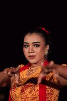 scherp ogen van Indonesisch Dames met bedenken terwijl vervelend een oranje jurk Bij de dansen festival foto