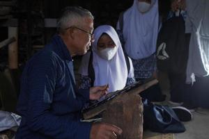 keris ambachtslieden zijn onderwijs bezoekers over de werkwijze van maken keris in de werkplaats. bantul, Indonesië - 25 augustus 2022 foto