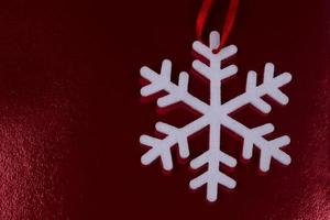 wit sneeuwvlok Aan een rood glimmend Kerstmis achtergrond. foto